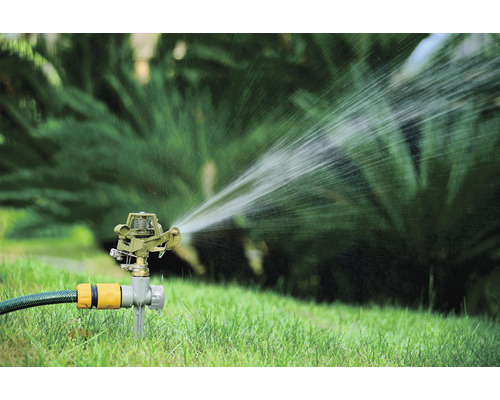Zavlažovač trávníku zavlažuje trávník v zahradě.