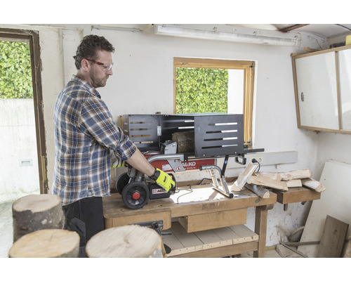 Muž obsluhuje štípačku dřeva na ponku a štípe dřevo.