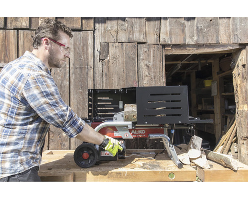 Muž obsluhuje štípačku dřeva AL-KO před dřevěnou stěnou.