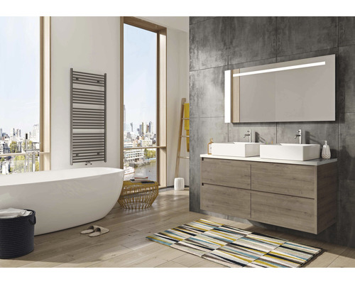 Světlá koupelna s vanou, skříňkou pod umyvadlo, zrcadlem a ohřívačem ručníků.