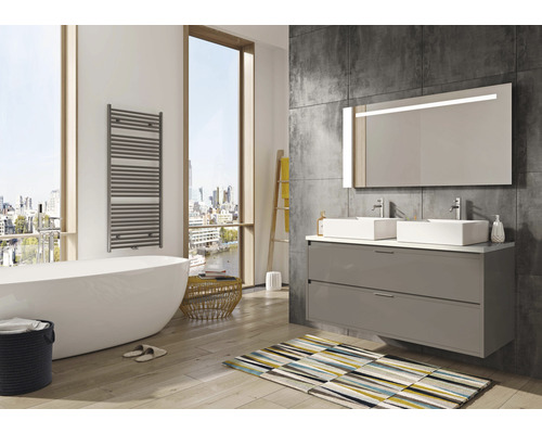 Moderní koupelna s vanou, umyvadlovou skříňkou se dvěma umyvadly a osvětleným zrcadlem.