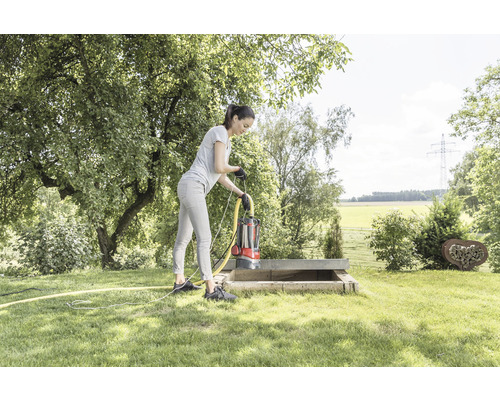 Žena obsluhuje ponorné čerpadlo v betonové šachtě na zahradě.