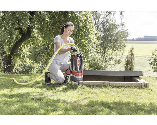 Žena připojuje ponorné čerpadlo AL-KO k hadici na zahradě