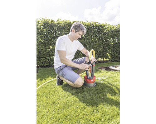 Muž klečí na trávníku a připojuje žlutou hadici k ponornému čerpadlu Al-Ko.