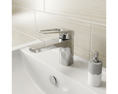 Lesklá umyvadlová baterie na umyvadle s dávkovačem mýdla.