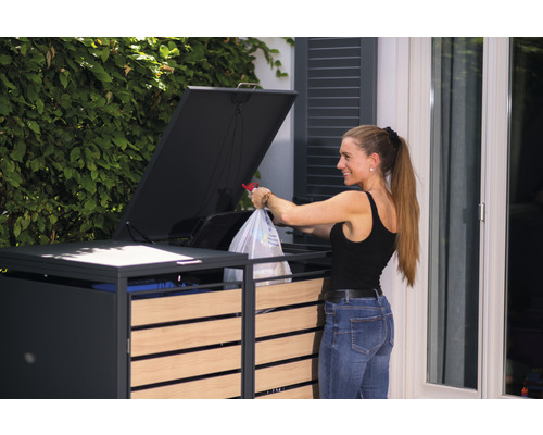 Žena vyhazuje odpadky do nádoby na odpadky s dřevěnými prvky a sklopným víkem