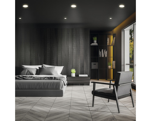 Ložnice s postelí, křeslem a knihovnou v tmavém provedení