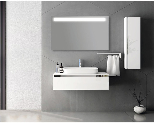 Moderní koupelna s bílým umyvadlem, osvětleným zrcadlem a vysokou skříní.