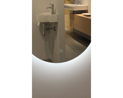 Detail koupelny s kulatým zrcadlem s LED osvětlením, umyvadlem a baterií