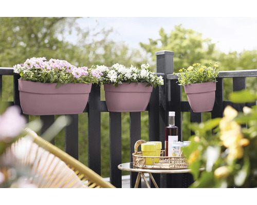 Tři osázené balkónové truhlíky visí na zábradlí