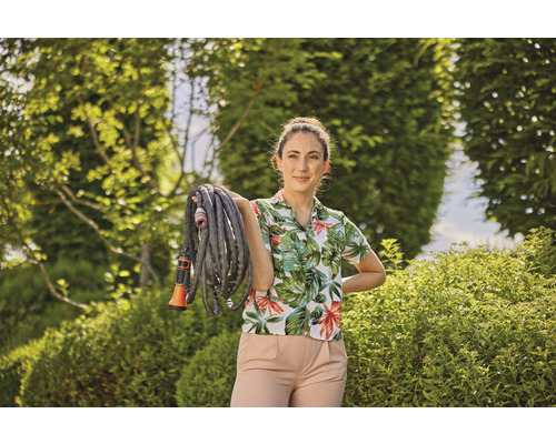 Žena drží zahradní hadici na zahradě