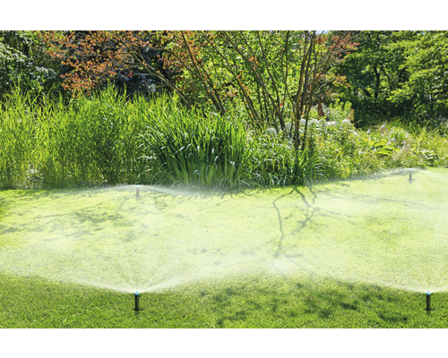 Zavlažovače zavlažují zelený trávník v zahradě.