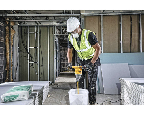 Stavební dělník míchá tmel s míchadlem na staveništi.