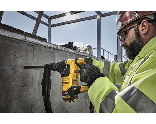 Stavební dělník vrtá otvor do betonové stěny pomocí vrtacího kladiva DeWalt.