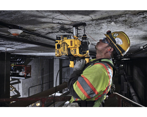 Stavební dělník vrtá jádrovou vrtačkou DeWalt otvor do betonového stropu.