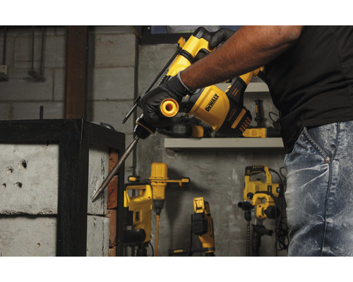 Muž používá bourací kladivo DeWalt k vrtání do cihlové zdi.