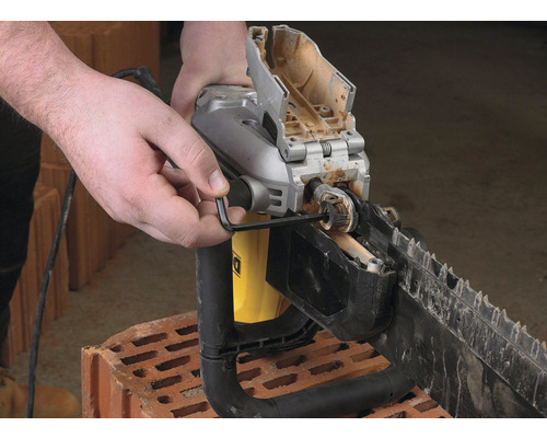 Muž nastavuje napnutí řetězu pily na kámen pomocí imbusového klíče.