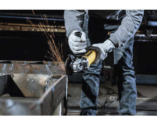 Osoba brousí kov úhlovou bruskou DeWalt, létají jiskry.