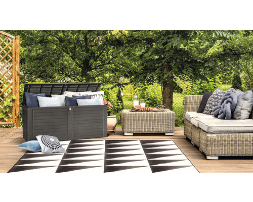 Zahradní scéna s boxem na polstry, stolem, pohovkou a kobercem na dřevěné terase