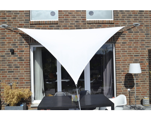 Trojúhelníková sluneční plachta před stěnou domu se zahradním nábytkem