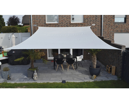 Obdélníková sluneční plachta z látky nad terasou se stolem a židlemi