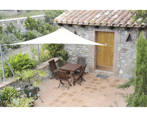 Exteriér s trojúhelníkovou sluneční plachtou, stolem a židlemi na terase.