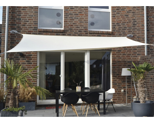 Scéna se sluneční plachtou nad zahradním stolem před domem