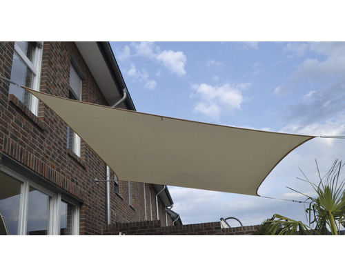 Béžová sluneční clona na cihlové budově s modrou oblohou