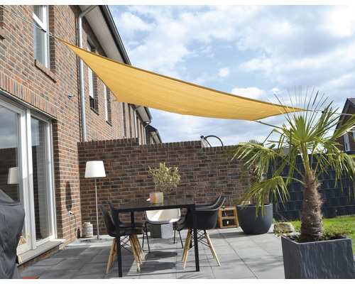 Terasa se sluneční plachtou, stolem a židlemi před domem