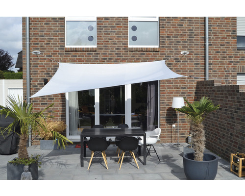 Terasa se sluneční plachtou, stolem a židlemi před domem