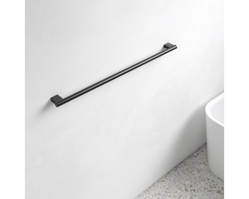 Černý držák na ručníky na bílé zdi v koupelně.