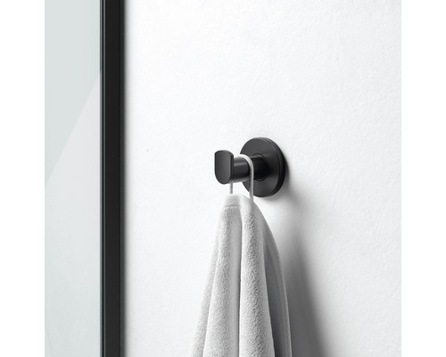 Černý háček na ručníky s ručníkem namontovaným na zdi
