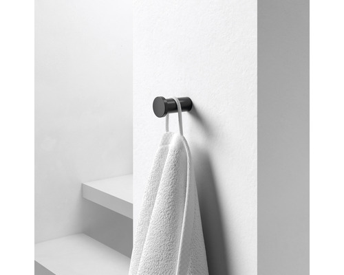 Černý háček na ručníky s ručníkem na zdi