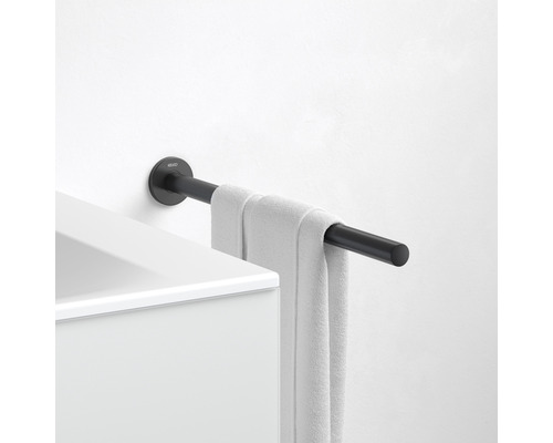 Černý držák na ručníky s ručníkem namontovaný na bílé zdi