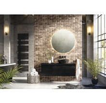 Moderní koupelna s volně stojící vanou, radiátorem na ručníky, skříňkou pod umyvadlo, kulatým zrcadlem s osvětlením a cihlovou zdí