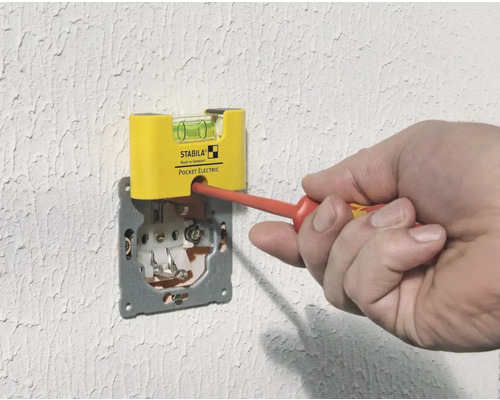 Řemeslník seřizuje zásuvku pomocí šroubováku a vodováhy
