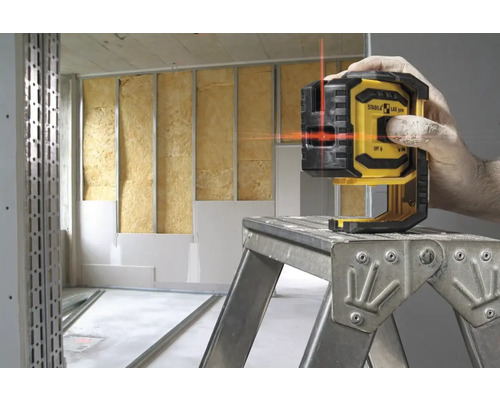 Logo společnosti Stabila. Osoba používá čárový laser v místnosti ve stavu hrubé stavby.