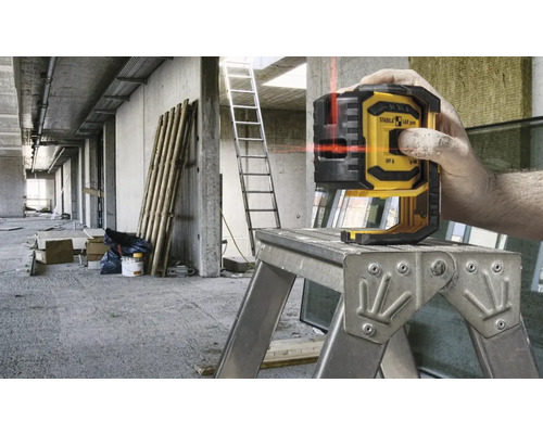 Liniový laser Stabila na pracovní plošině v hrubé stavbě.
