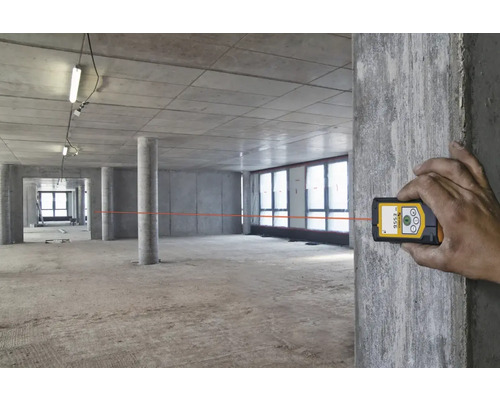 Místnost ve výstavbě s rukou ovládající laserový dálkoměr