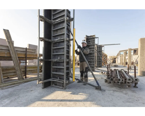 Stavební dělník upravuje betonové bednění pomocí vodováhy na staveništi.