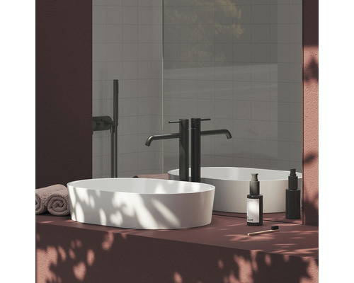 Moderní koupelna s umyvadlem na desku, vodovodní baterií, zrcadlem a ručníky.