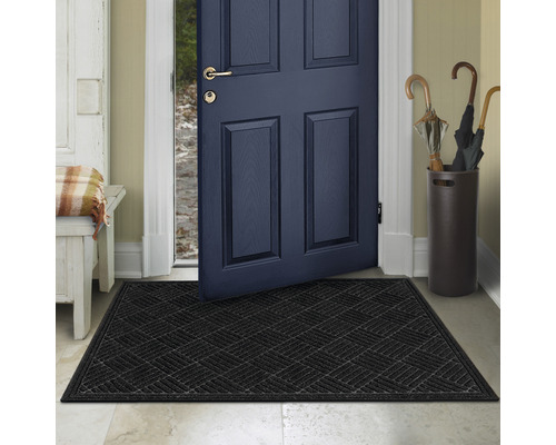 Černá rohožka před otevřenými vchodovými dveřmi
