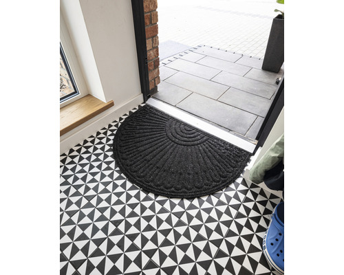 Půlkruhová textilní rohožka před vchodovými dveřmi na podlaze s geometrickým vzorem
