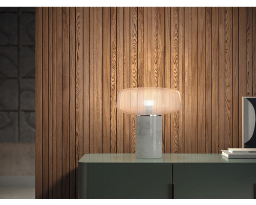 Dekorativní stolní lampa z mramoru a skla na komodě před dřevěnou stěnou