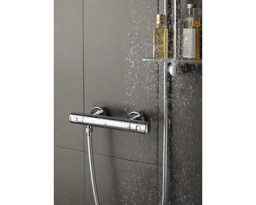 Nástěnná sprchová baterie se sprchovou hadicí a lahvemi šamponu ve sprchovém koutě