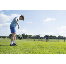 Mladík žongluje s fotbalovým míčem na fotbalovém hřišti.