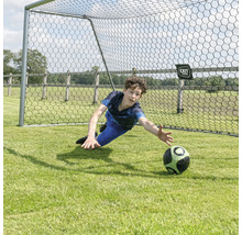 Chlapec drží fotbalový míč před fotbalovou brankou.