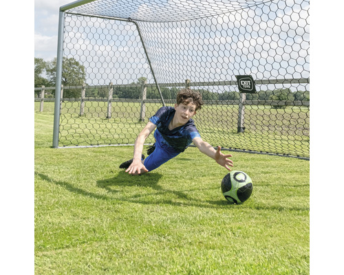 Chlapec drží fotbalový míč před fotbalovou brankou.