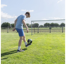 Mladík si hraje s fotbalovým míčem před fotbalovou brankou na zahradě