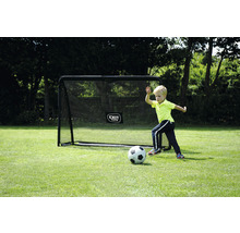 Chlapec hraje fotbal před fotbalovou brankou na zahradě.